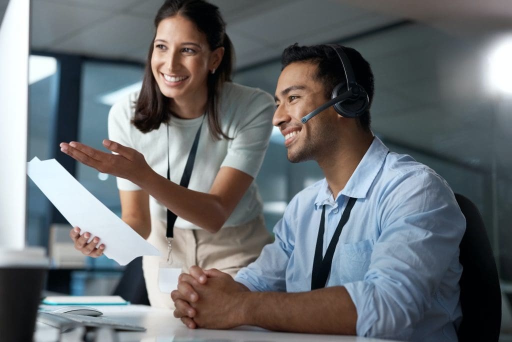 Shot of a young man and woman reading a document while working in a call centre