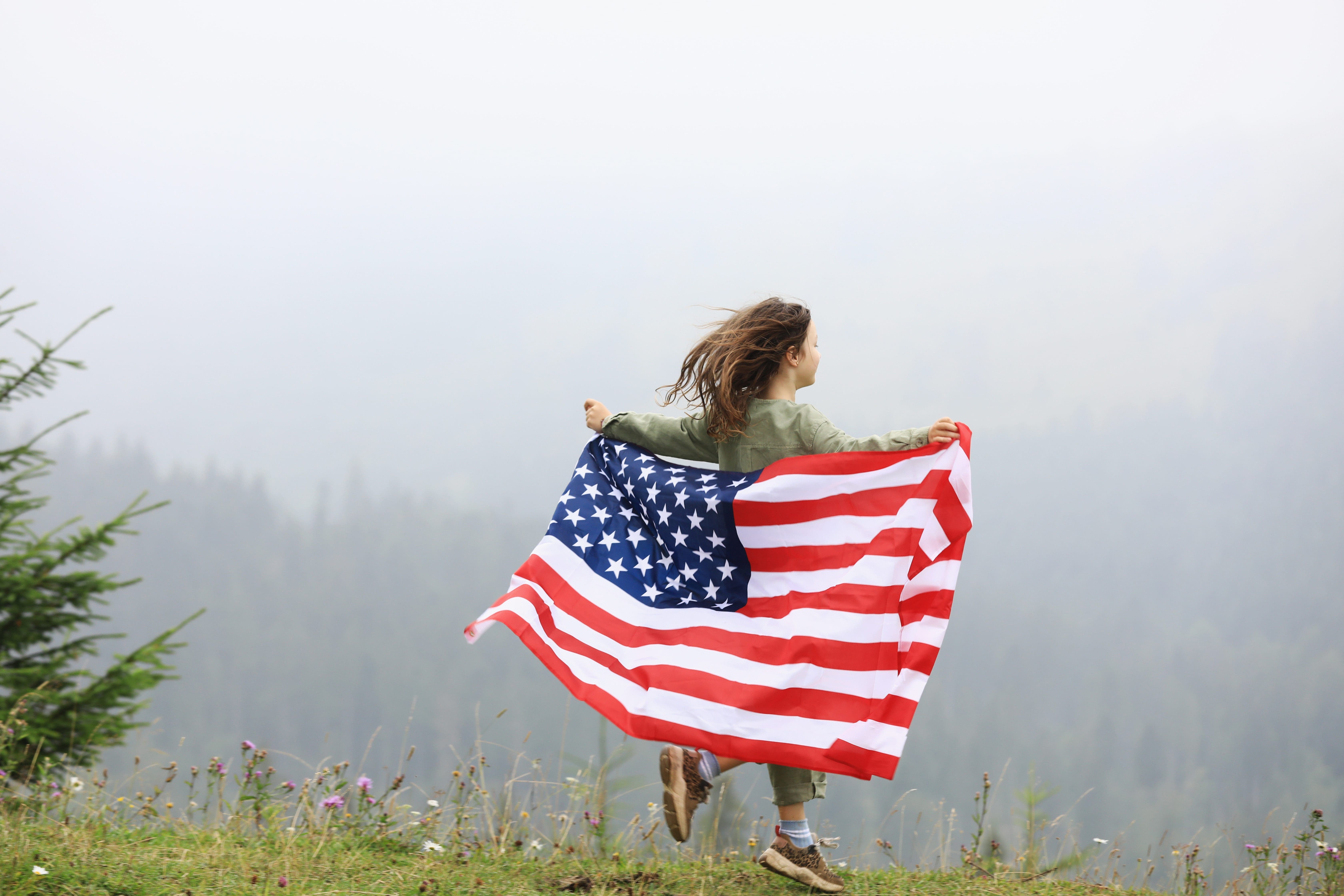 Happy adorable little girl smiling and waving American flag. Patriotic holiday. Happy kid, cute